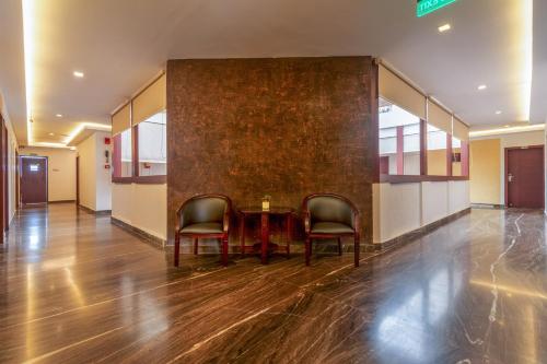 a hallway with two chairs and a table in a building at Zip By Spree Hotels Mangala Towers Thrissur in Trichūr