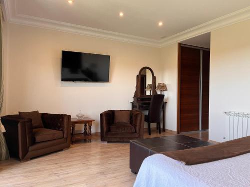 a bedroom with a bed and two chairs and a television at Hotel Rural Playa de Aguilar in Muros de Nalón