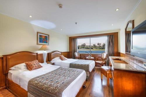 a hotel room with two beds and a flat screen tv at Horus Eye Nile Cruse in Luxor