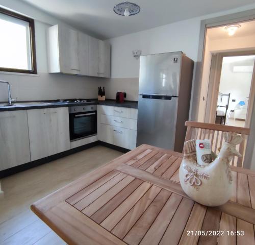 a kitchen with a wooden table and a refrigerator at Villa Su Giudeu in Chia