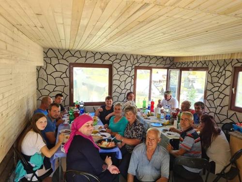 un grupo de personas sentadas en una mesa en un restaurante en Koliba Nazif Softić, en Fojnica