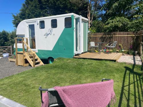 a green and white trailer parked in a yard at Pant y Rhedyn Glamping and camping site in Abergele