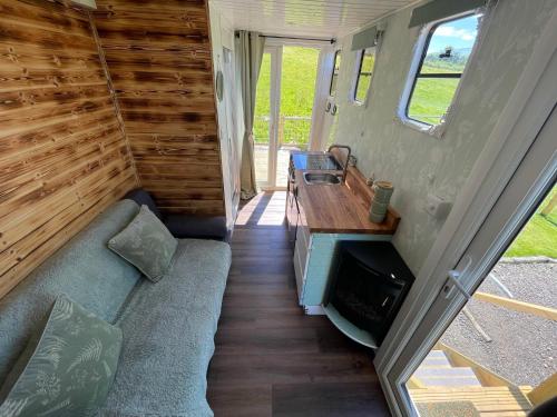 una sala de estar de una casa pequeña con sofá en Pant y Rhedyn Glamping and camping site, en Abergele
