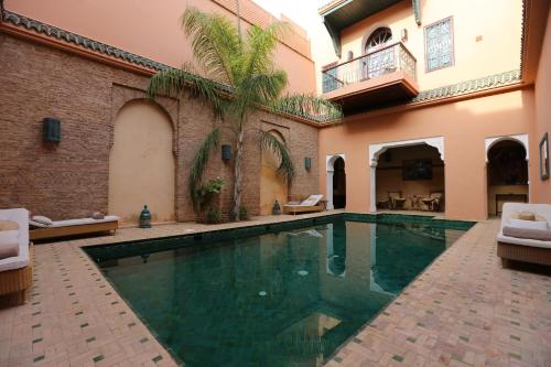 a swimming pool in a courtyard with a house at Palais Riad Lamrani in Marrakesh