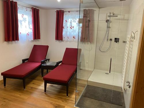 two red chairs in a bathroom with a shower at Ferienhaus Alex in Wiesing