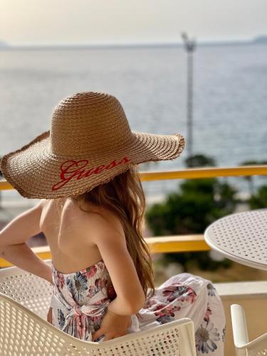 a woman sitting in a chair wearing a straw hat at Hotel Lungomare in Vlorë