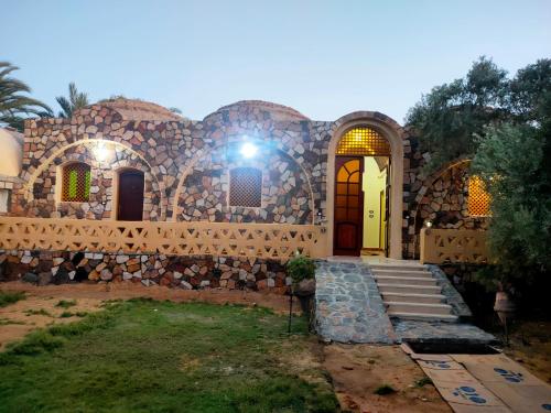 a home with a stone building with a light at Ahmed Safari Camp in Bawiti