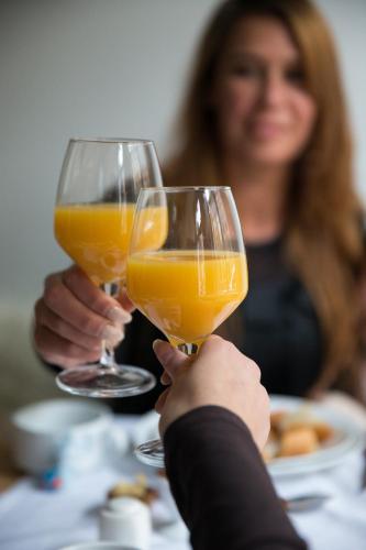 a woman holding up two glasses of orange juice at Stadslogies City Apartment Monsieur Philippe in Leeuwarden