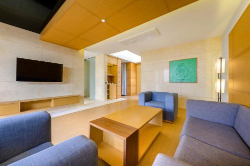a living room with chairs and a table and a tv at STANFORD Hotel & Resort Jeju in Jeju