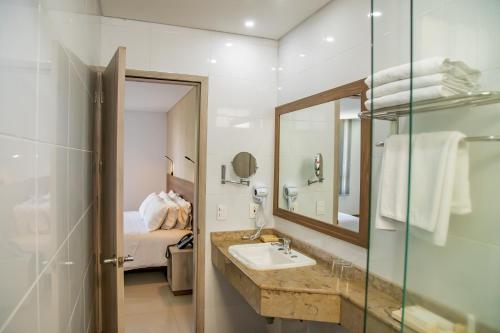 a bathroom with a sink and a mirror and a bed at Hotel Estancia Chipichape Cali in Cali