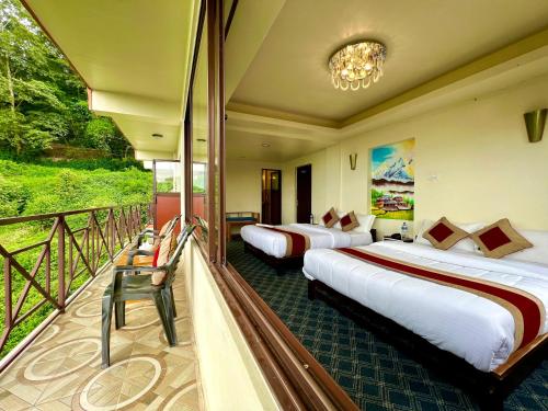 two beds in a hotel room with a balcony at Hotel Sakura Durbar in Nagarkot
