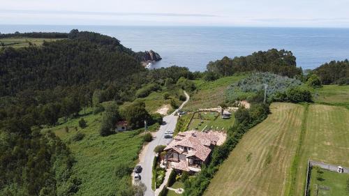 - une vue aérienne sur une maison située sur une colline à côté de l'océan dans l'établissement Hotel Rural Playa de Aguilar, à Muros de Nalón
