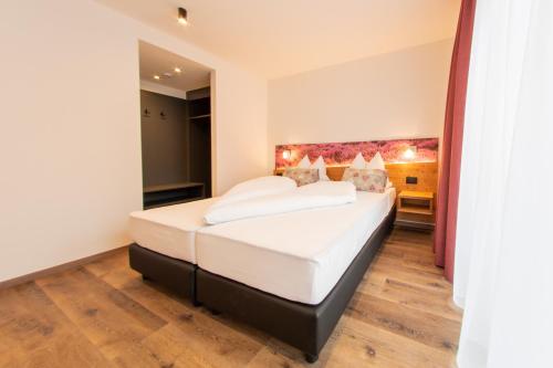 a bedroom with a large bed with white sheets at Hotel Gran Pre in San Vigilio Di Marebbe