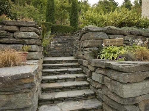 a stone retaining wall with a stone staircase in a yard at Pencarrow Boutique Lodge in Queenstown