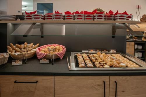 a counter with many different types of donuts and baskets at Hotel Gran Pre in San Vigilio Di Marebbe