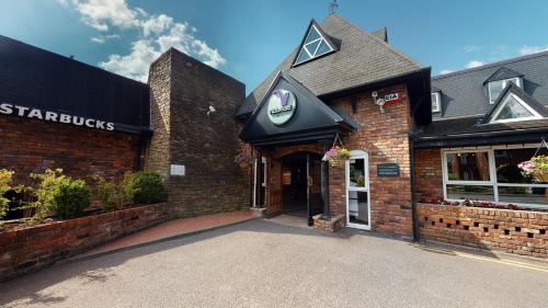 a store front of a brick building with a sign on it at Village Hotel Manchester Hyde in Hyde