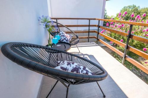 a chair on a balcony with pink flowers at Le Petit 2 in Cilipi