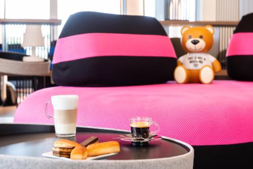 a table with a tray of food and a teddy bear on a bed at Hôtel Omnubo Collection in Les Épesses