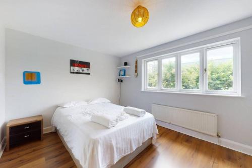 a white bedroom with a bed and a window at Spacious 4 bedroom home with garden in London in London