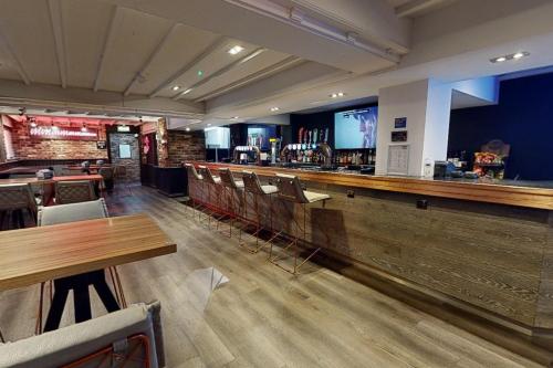 a bar in a restaurant with tables and chairs at Village Hotel Manchester Hyde in Hyde