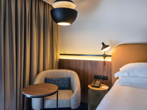 a hotel room with a bed and a chair and a table at Crowne Plaza - Nice - Grand Arenas by IHG in Nice