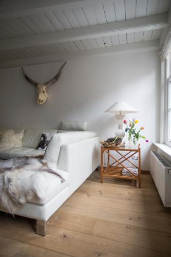 a white bedroom with a bed and a table at Sterlogies De Rozenboom in Leeuwarden