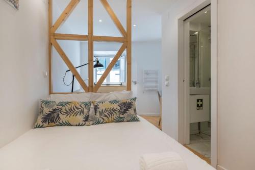 - une chambre avec un lit blanc et une tête de lit en bois dans l'établissement Alfama's Heart Studio by LovelyStay, à Lisbonne