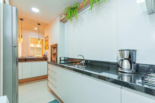 a kitchen with white cabinets and a black counter top at Ótima localização - @stayhousetemporada in Canela