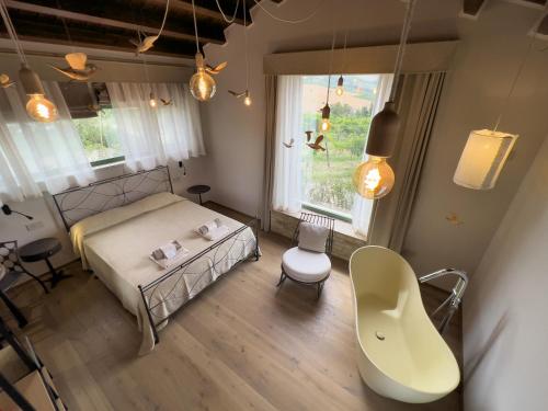 a bedroom with a bed and a chair and a window at Relais Cocci Grifoni - Panoramic Wine Resort in Offida