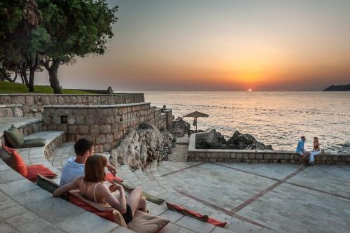 a group of people sitting on the steps watching the sunset at Radisson Resort Ruza Vjetrova in Dobra Voda