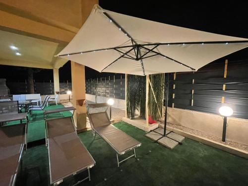 a room with tables and chairs and an umbrella at Villa Torre Magaggiari in Cinisi
