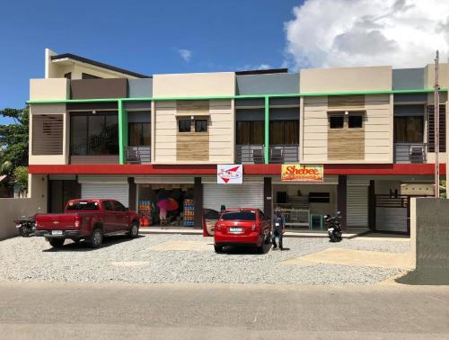 a building with two cars parked in a parking lot at Drew Hostel in Tagbilaran City