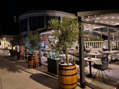 a restaurant with tables and chairs and trees in barrels at Hotel Millenium deluxe in Selce