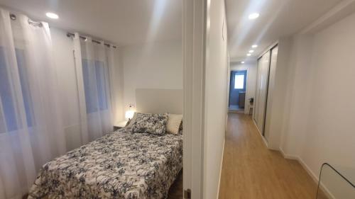 a small bedroom with a bed and a hallway at Escondite de Leire - Precioso piso reformado, Wifi 2h in Gijón