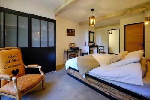 a bedroom with a large bed and a chair at Séjour LUXE pour couple avec PISCINE INTÉRIEURE terrasse SPA privé Green de GOLF in Alzonne