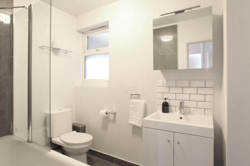 a white bathroom with a toilet and a sink at Lovely two bedroom apartment in London Old Street in London