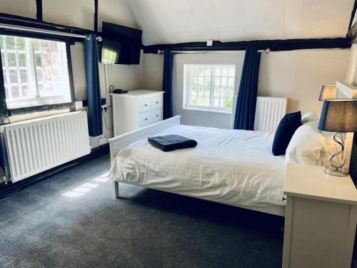 a bedroom with a white bed and two windows at George and Dragon in Horsham