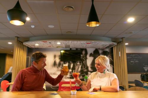 a man and a woman sitting at a table with drinks at ibis De Haan in De Haan