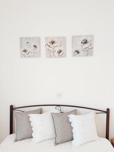 a white wall with three pictures above a bed with pillows at Intimate Olympus House in Litochoro