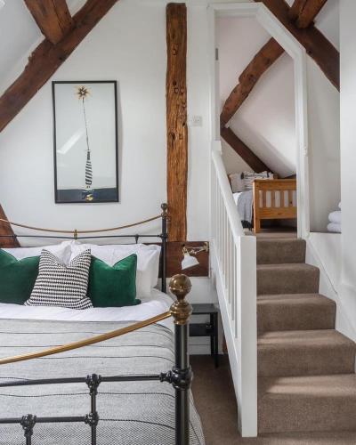 a bedroom with a bed with green pillows and a staircase at The Old Fire Station Ludlow in Ludlow