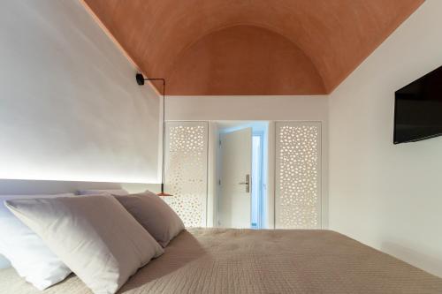 a bedroom with a bed with a wooden ceiling at Kykladonisia Traditional Settlement in Fira