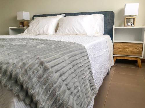 ein Bett mit einer weißen Bettdecke und zwei Nachttischen in der Unterkunft Brand New Chic Appt in Mindelo at Great Rates in Mindelo
