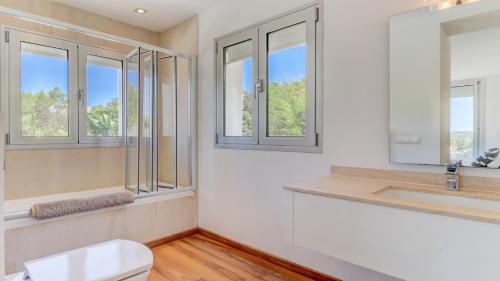 a bathroom with a toilet and a sink and windows at Villa Vista in Crestatx