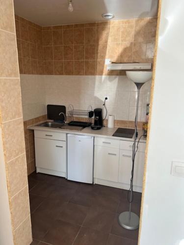 une petite cuisine avec des armoires blanches et un évier dans l'établissement appartement tout équipé proche de la gare de Narbonne, à Narbonne