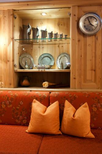 a couch with two pillows in a room with a clock at Hotel Astras in Scuol