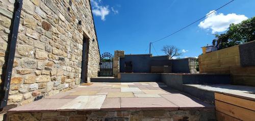 a building with a stone wall and a brick sidewalk at Rucastle Apartment in Ingleton
