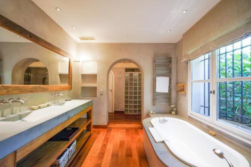a bathroom with a sink, tub, and a window at Domaine Les Mésanges in Saint-Tropez