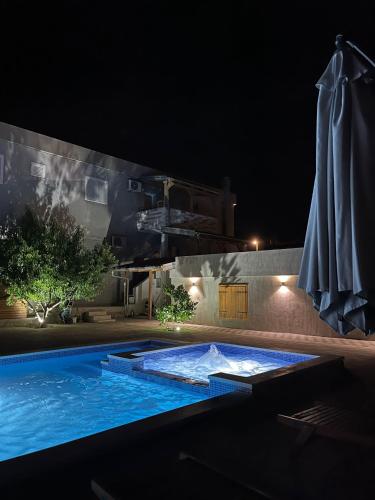 a swimming pool at night with an umbrella and a swimming pool at Apartmani Mia in Drage