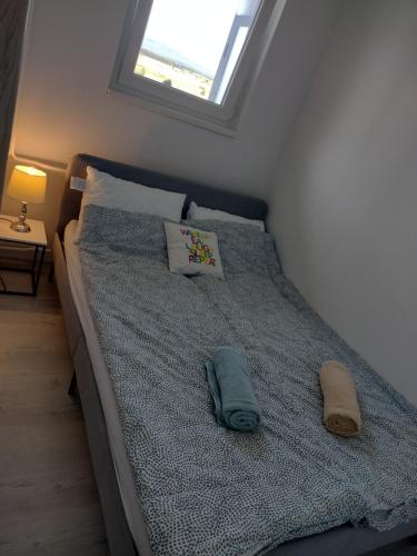 a bedroom with a bed with two pillows and a window at Kilátó Apartman in Tapolca