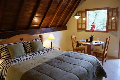 a bedroom with a large bed and a table at Pousada do Castelo in Monte Verde